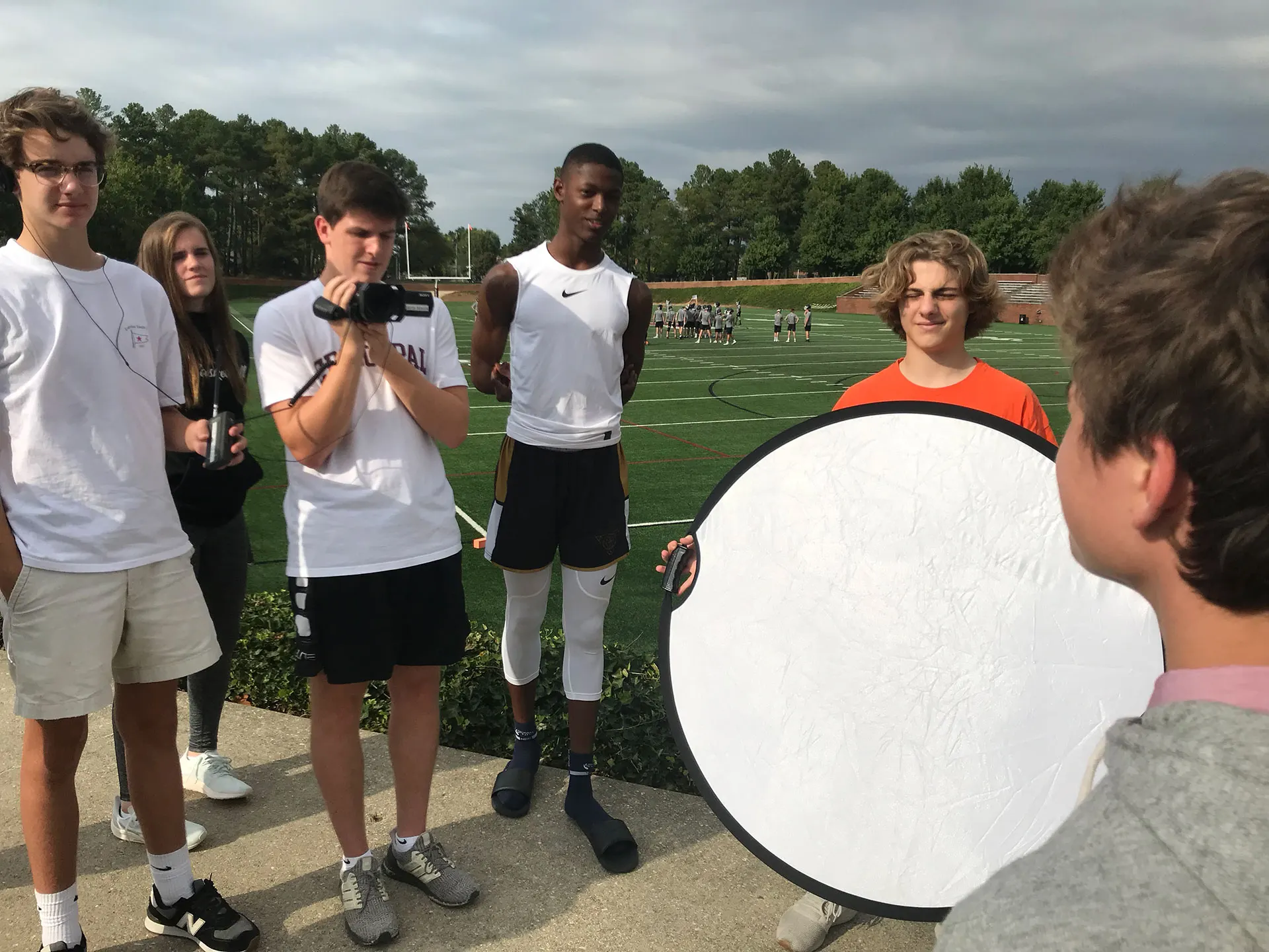 A student videographer framing a shot from the stands.